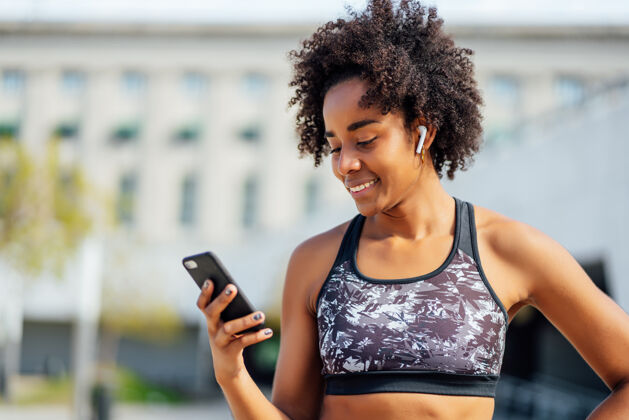 锻炼一位非洲运动女性在户外锻炼后使用手机放松身心非洲运动装放松