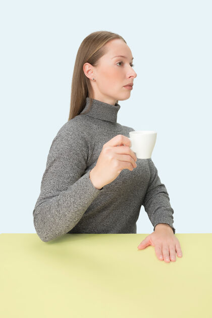 抱着美丽孤独的女人坐着 手里拿着一杯咖啡 看起来很悲伤极简风格的特写调肖像年轻放松随意