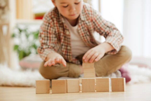 童年坐在地板上的小孩漂亮的男孩在家里玩木制立方体概念图像与复制或负空间和模拟你的文字幼儿园负幼儿园