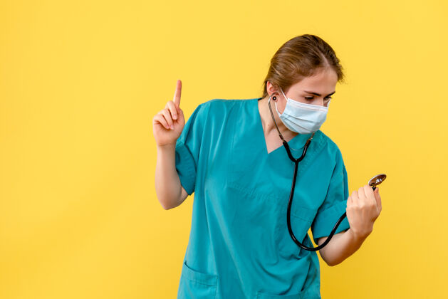 冠状病毒正面图黄色背景上戴面罩的女医生健康大流行药仪器护士