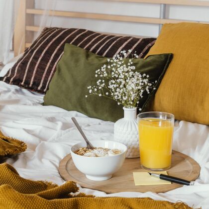麦片带果汁杯的床上早餐菜美味床和早餐