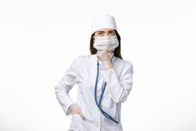 到期正面图：女医生穿着白色无菌医疗服 戴着口罩 因为柯维德-深入思考白墙疾病柯维德-大流行病毒疾病思考冠状病毒预防医生