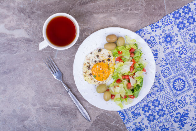 食物煎鸡蛋和绿色沙拉配一杯茶晚餐午餐健康