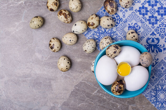 新鲜各种各样的鸡蛋在灰色的杯子表面传统盘子有机