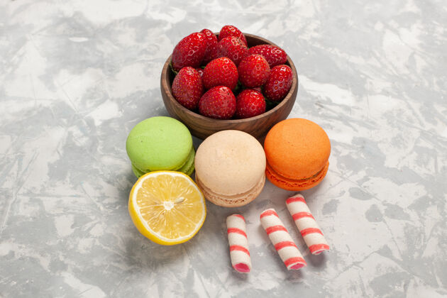 食品正面图法国麦卡龙 白色表面有新鲜草莓水果浆果蛋糕饼干甜甜的糖草莓饮食麦卡龙