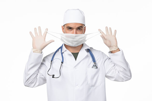 灯光正面图：男医生穿着医疗服 戴着口罩 因柯维德-轻壁病病毒柯维德-大流行病外套套装视图