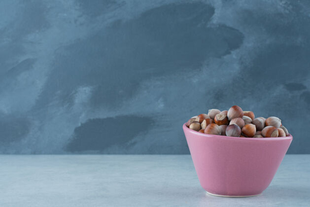 可口在大理石背景上放满坚果的粉红色小盘高质量照片坚果吃盘子