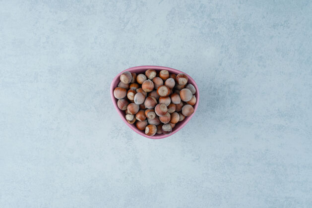 大理石在大理石背景上放满坚果的粉红色小盘高质量照片健康可口可食用