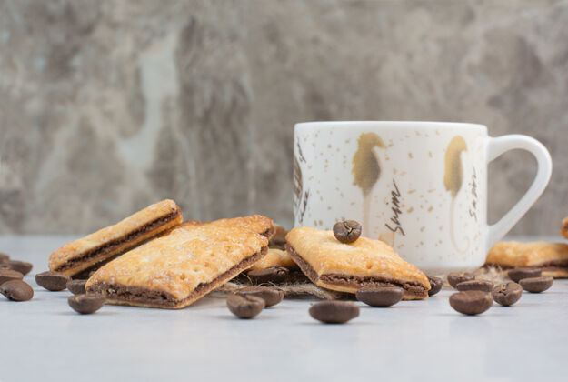 杯子白色背景上有饼干和咖啡豆的白色咖啡杯高品质照片美味热的豆子