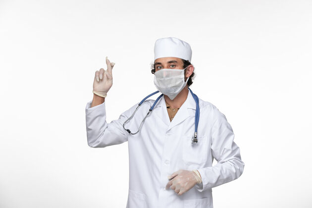 男性正面图身穿医疗服的男医生戴着口罩 以防白墙病毒的传播视图冠状病毒面具