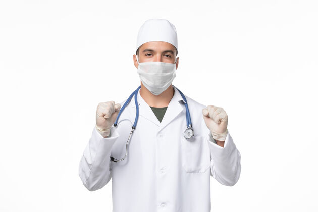 医生正面图：男医生穿着医疗服 戴着口罩 对抗白色墙壁上的冠状病毒病医学大流行男性冠状病毒大流行