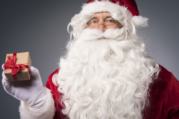 圣诞节圣诞老人带着一个小礼品盒看着相机男人冬天