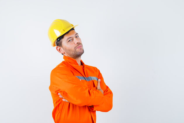 工头穿着制服的建筑工人 戴着头盔交叉着双臂站着 看上去很自信 正对着前方承包商团队开发
