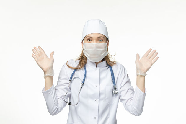 疾病正面图女医生穿着医疗服 戴着口罩和手套 由于白色办公桌上的冠状病毒疾病大流行健康冠状病毒女性医生制服