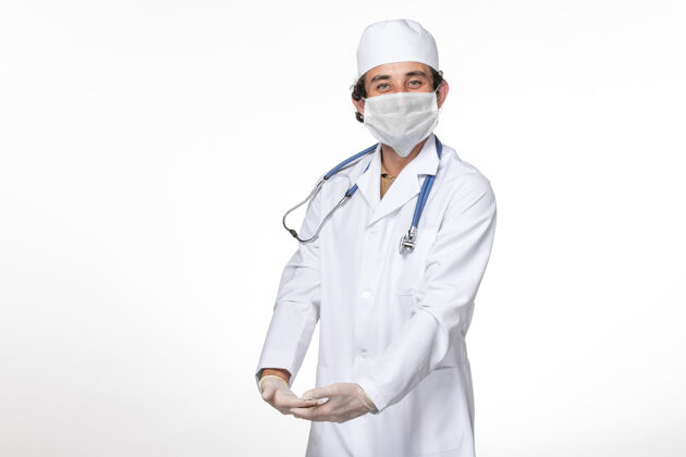冠状病毒正面图：男医生穿着医疗服 戴着口罩 以防白色墙壁飞溅病毒冠状病毒大流行防护笑视图