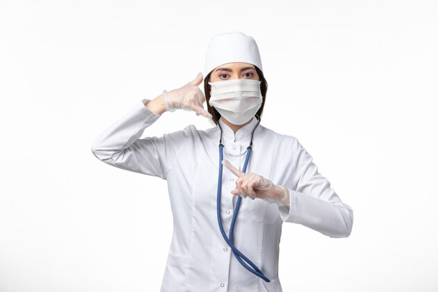 冠状病毒正面图女医生身穿白色无菌医疗服 带口罩 因冠状病毒轻染白墙大流行性疾病冠状病毒医生视图女性