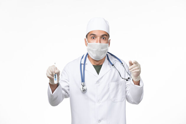 设备正面图：男医生穿着医疗服 戴着防冠状病毒口罩 手持白墙病毒-冠状病毒-大流行医疗查看前面