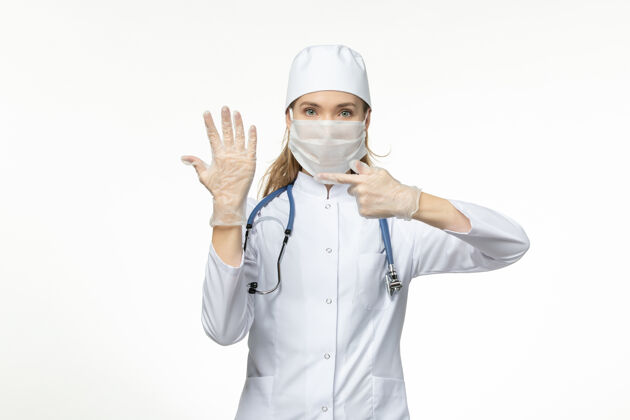 正面正面图女医生穿着医疗服戴着口罩和手套因冠状病毒白壁病病毒冠状病毒-大流行性疾病女性专业医疗