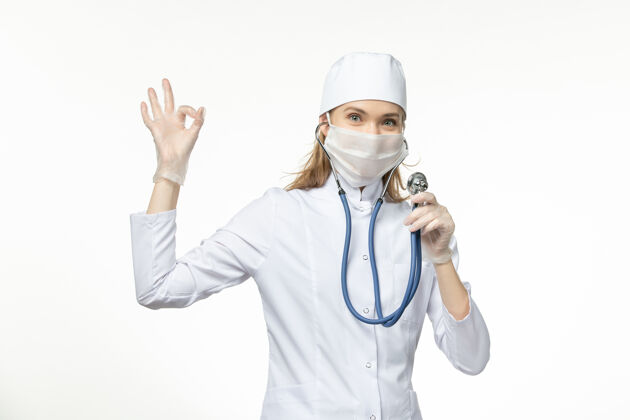医生前视图穿着白色医疗服的女医生在桌上使用听诊器疾病传播制服医疗冠状病毒