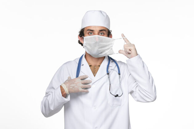大流行正面图男医生穿着医疗服戴着口罩上白墙冠状病毒大流行药外套男性视图