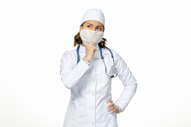 外套正面图女医生穿着白色医疗服 戴着口罩 因思考冠状病毒对白墙大流行性疾病的隔离作用女性医生疾病
