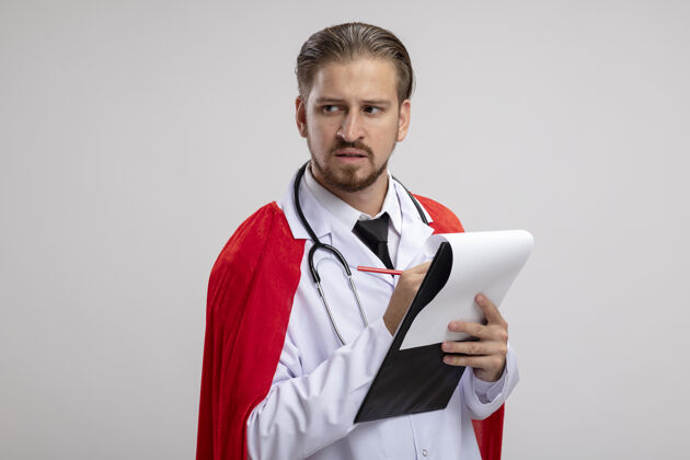 医疗年轻的超级英雄穿着医用长袍拿着听诊器拿着笔看着我剪贴板思考超级英雄