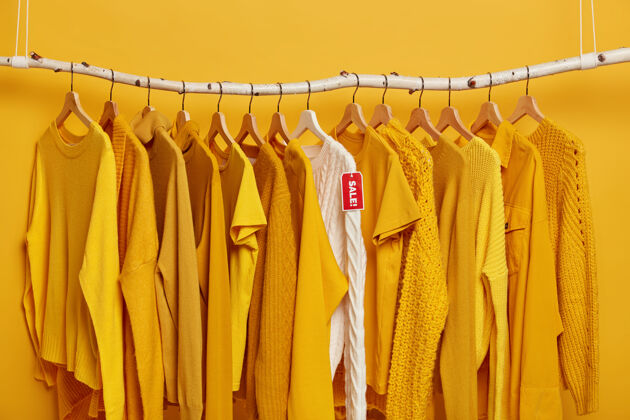 黄色购物和特价概念许多黄色衣服和白色针织毛衣与红色标签出售衣架销售羊毛