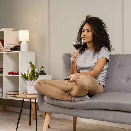 休闲坐在沙发上看电视喝酒的女人看电视电视遥控器女人