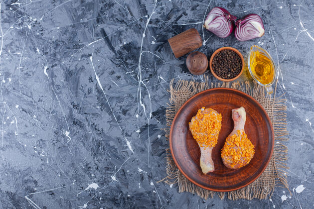 香料把腌好的鸡腿放在盘子里的麻布上 旁边放着香料和洋葱美味粗麻布家禽