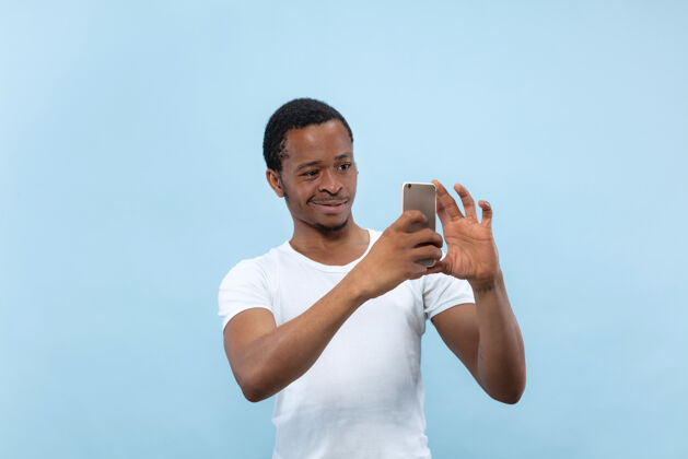 面部半身特写肖像的年轻非洲裔美国男子在白色衬衫的蓝色空间人类的情感 面部表情 广告概念专业人类男人