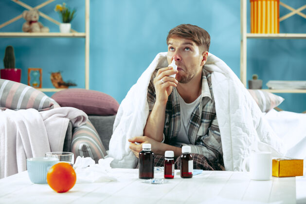 感冒留着胡须的病人坐在家里的沙发上 铺上暖和的毯子 用鼻喷雾剂对疾病 流感 疼痛有概念在家放松坐姿发烧疾病