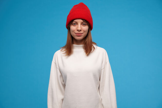 成人十几岁的女孩 酷酷的女人 深色头发穿着白色毛衣和红色帽子人和情感的概念看起来服装青少年