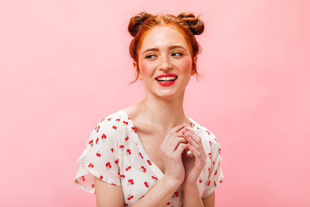 漂亮一位身穿樱桃t恤的红发女士笑着咬着粉色背景的手指美丽奢华时尚