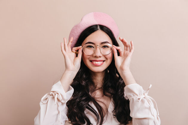 生活方式兴奋的日本女人戴着眼镜摆姿势美丽的亚洲女人戴着贝雷帽对着镜头大笑现代中国时尚