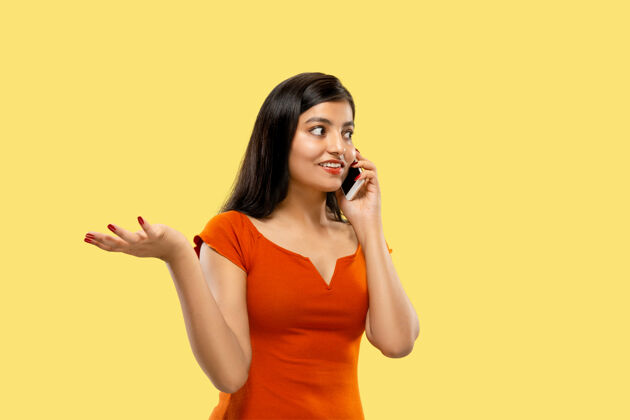 衣服美丽的女性半身像被隔离在黄色的空间里年轻感性的印度女人穿着衣服在电话里说话消极的空间女士女人惊喜
