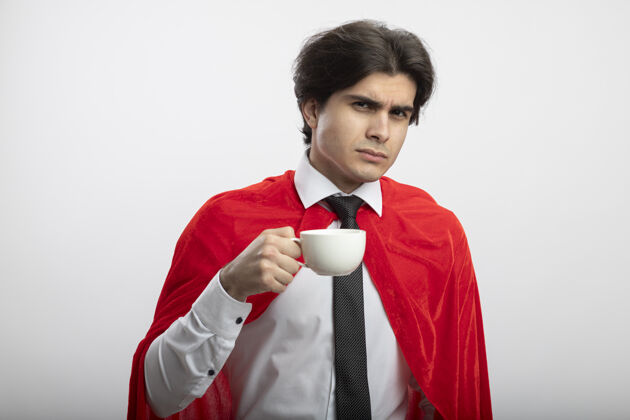 咖啡自信的年轻超级英雄 戴着领带 端着一杯咖啡 看着镜头小伙子看着抱着