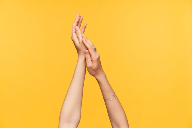 女性剪下的照片 年轻女性的手 皮肤白皙 修剪整齐 在涂奶油的时候被举起来 隔离在黄色背景上手和身体护理的概念沟通手臂护理