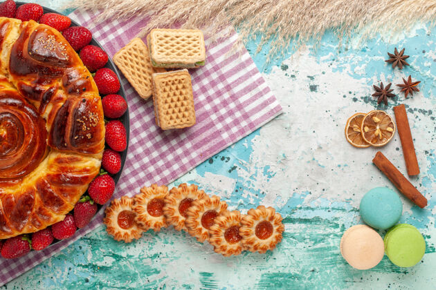 饼干俯瞰美味的派与红色草莓和华夫饼在蓝色的表面糖果糖果盘子