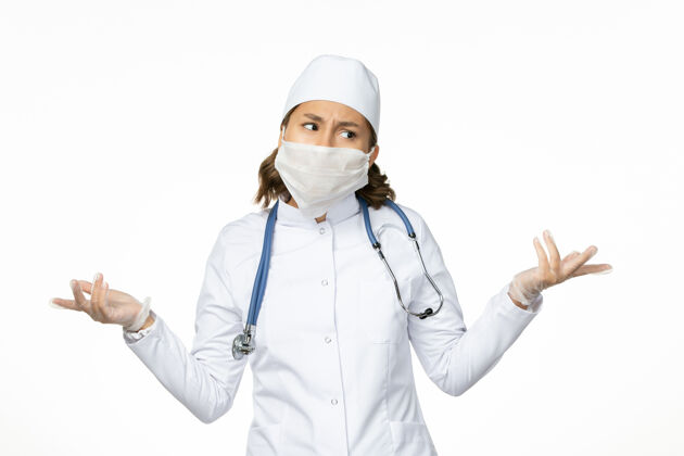 面罩白色办公桌上戴着无菌口罩和手套的年轻女医生大流行听诊器护士
