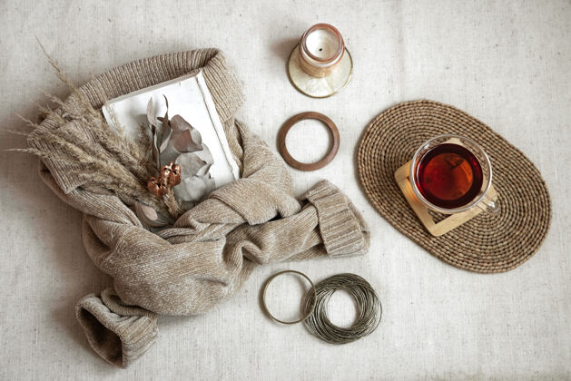 构图静物与女人的手镯 在柳条架上一杯茶 一支蜡烛和一件温暖的毛衣 秋天舒适概念俯瞰毛衣房子手镯