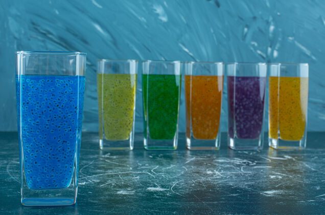 美味在蓝色背景上排成一排的果汁杯高质量的照片营养加工玻璃