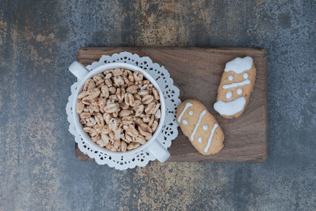 饼干两个圣诞饼干和一碗甜花生放在木板上高质量的照片小吃糕点甜点