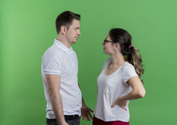 男人一对年轻的运动情侣站在绿色的墙上 看着彼此争吵夫妻每一个运动