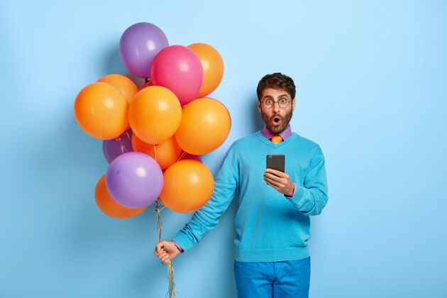 祝贺一个穿着蓝色毛衣拿着气球的傻家伙男人男人庆祝