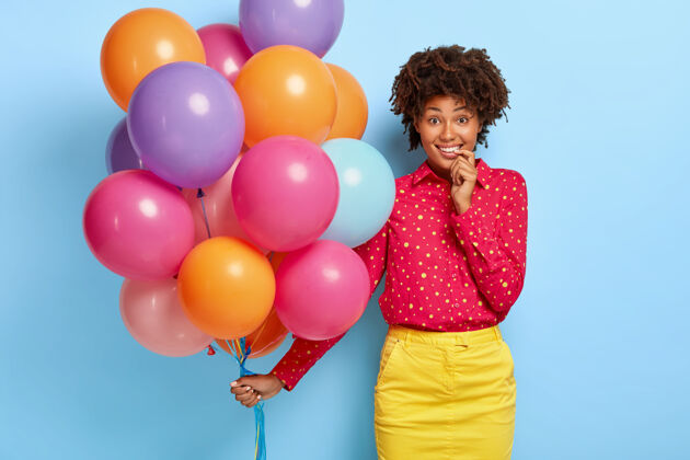 微笑女人开心的摆着五颜六色的气球拍照发型裙子生日
