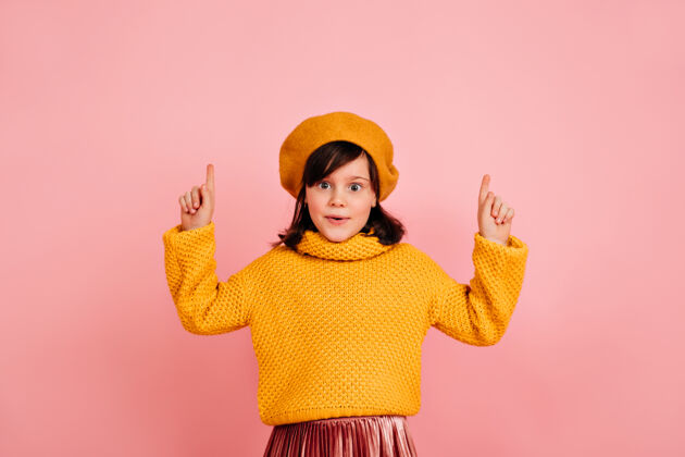 乐趣有趣的孩子小法国女孩在粉红色的墙上摆姿势贝雷帽积极人