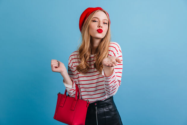 兴奋浪漫的法国女孩戴贝雷帽的时髦女人拿着红色手提包蓝色上孤立服装积极