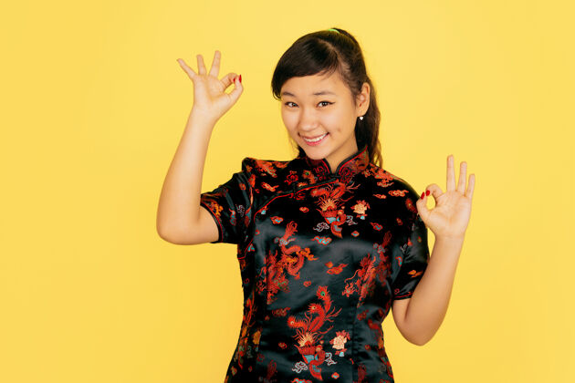 红色微笑可爱 展现美好中国新年快乐黄色背景上的亚洲少女肖像身着传统服装的女模特看起来很快乐庆祝 人类情感复制空间文案空间女性手