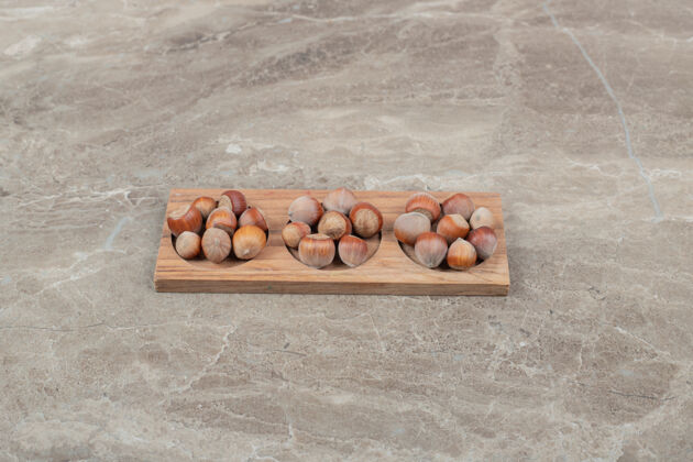生的一堆榛子在大理石背景上的木板上高质量的照片天然贝壳美味