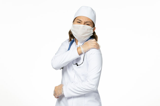女性正面图：年轻的女医生 戴着无菌口罩和手套 因为浅白色的桌子上有冠状病毒病毒手套面罩